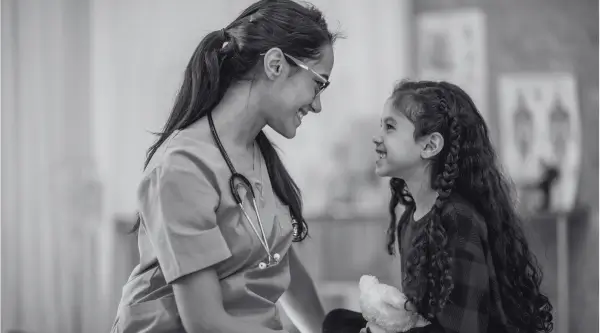 Friendly healthcare professional engaging with a happy child patient, illustrating a scene for B2 First speaking practice test.